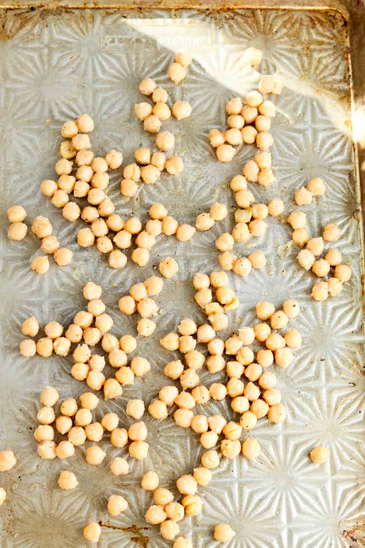 Chickpeas spread out on a sheet pan.