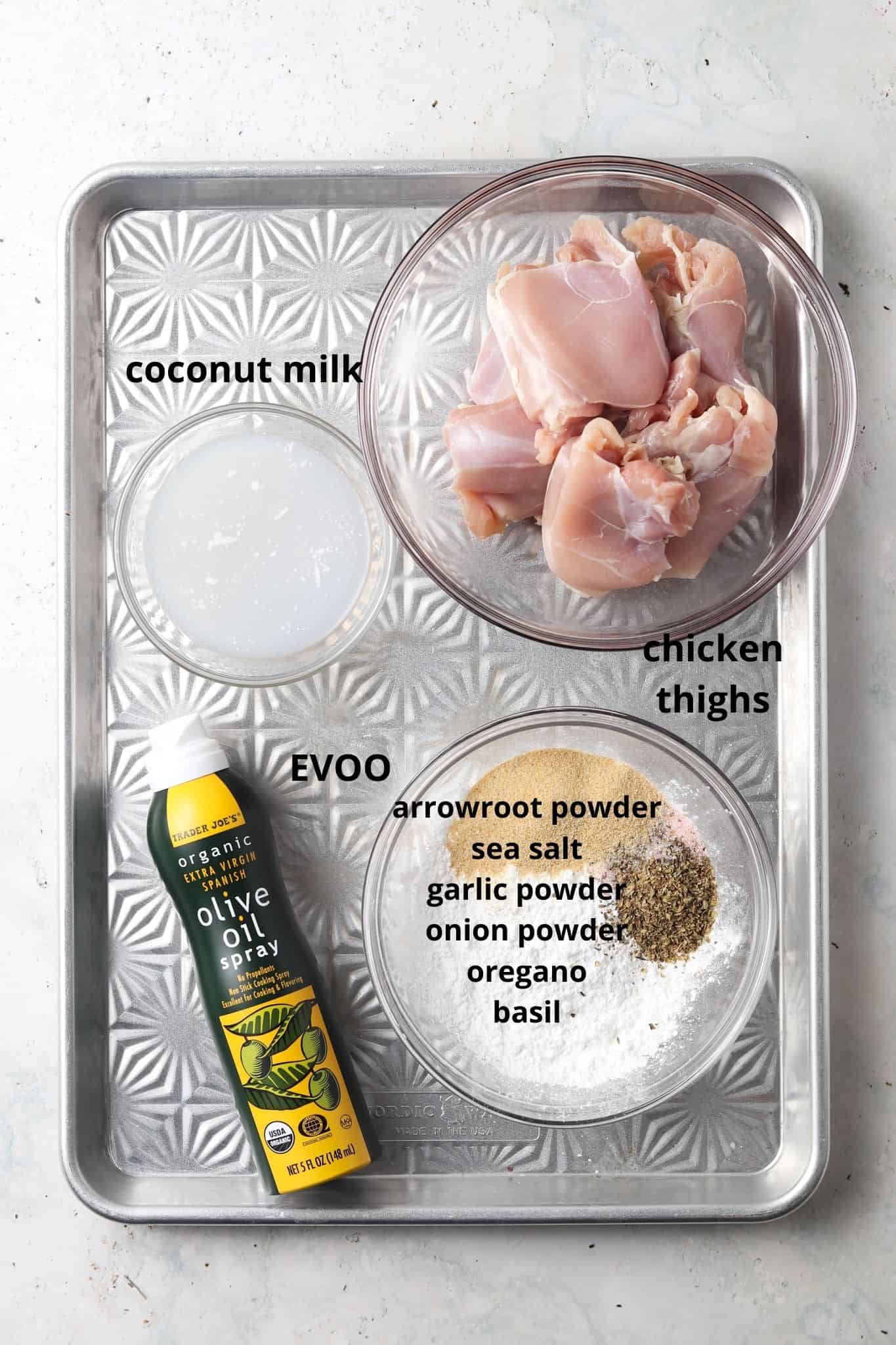 Ingredients needed for crispy garlic aip chicken thighs on a metal tray in small glass bowls.