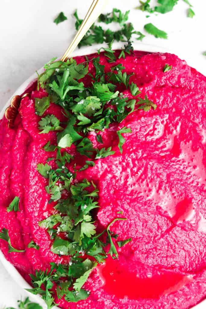 aip hummus with fresh parsley on top in a white bowl