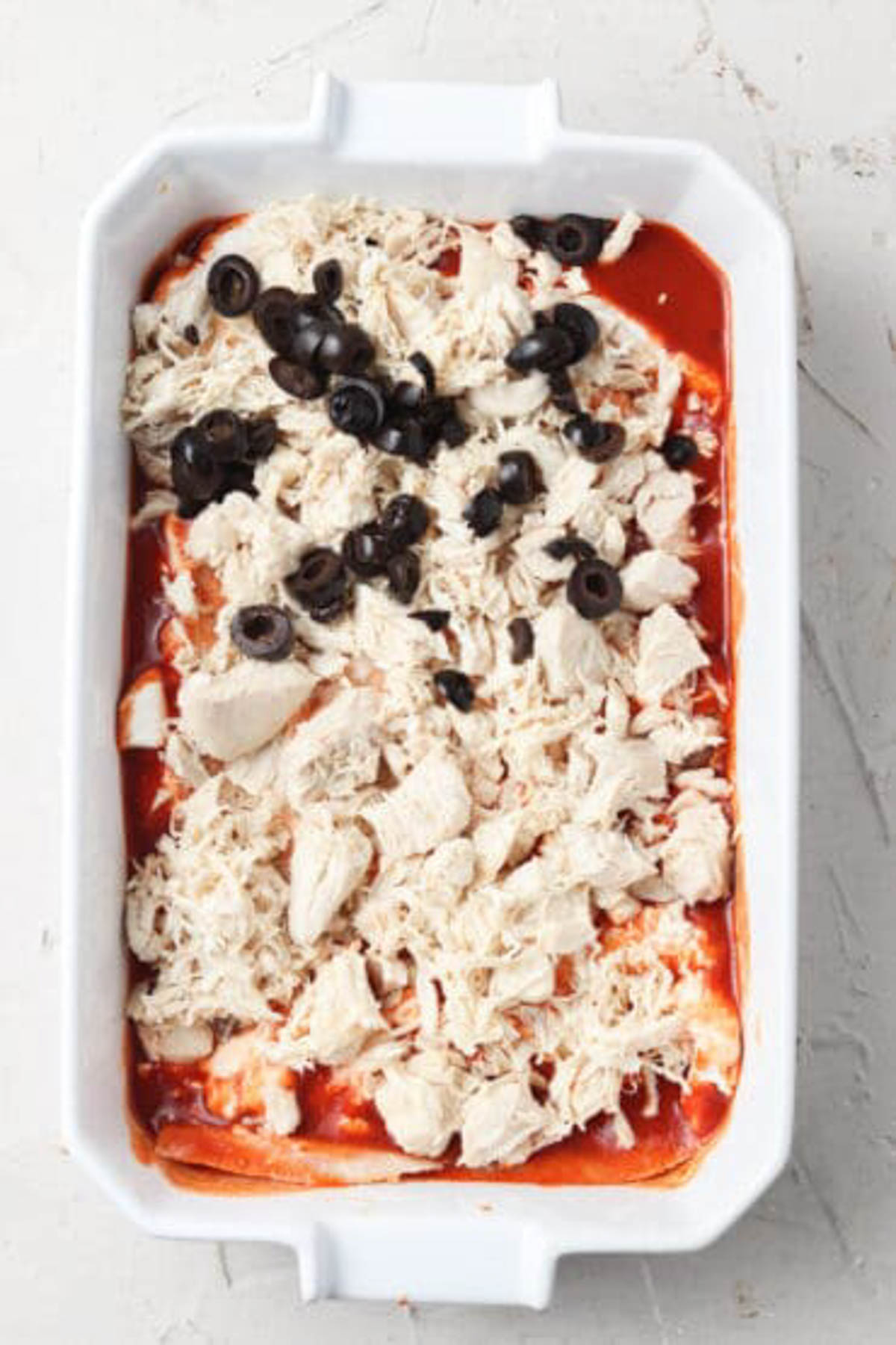 Dairy free enchiladas being assembled in a casserole dish.