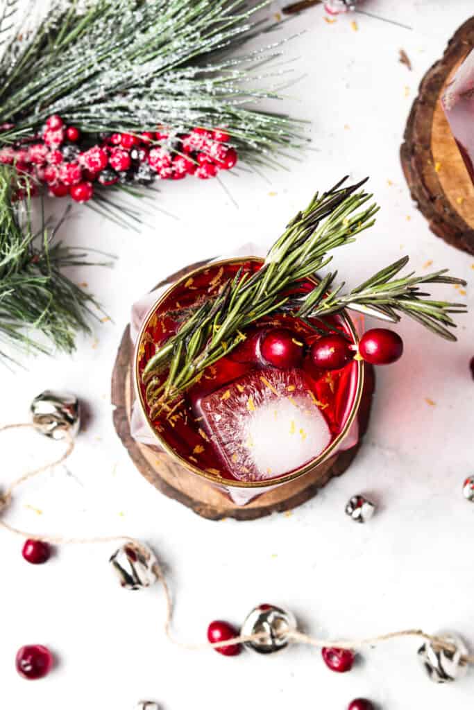 overhead shot of cranberry mocktails with bells, ice cube, and fresh cranberries