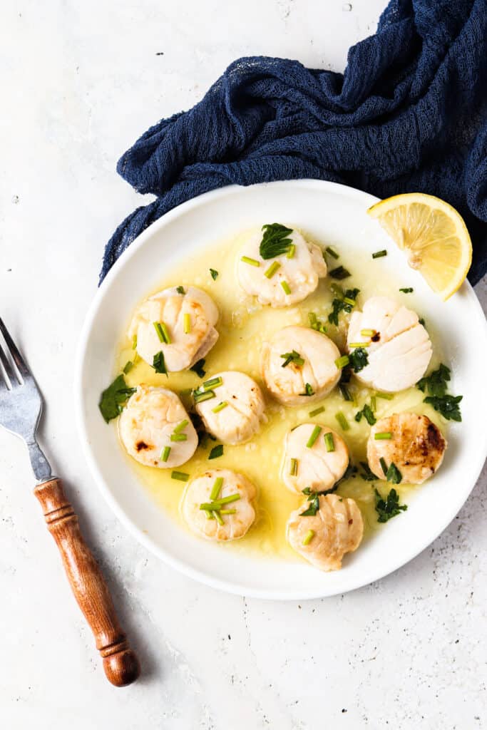 whole30 scallops overhead shot on a white plate with a tan fork