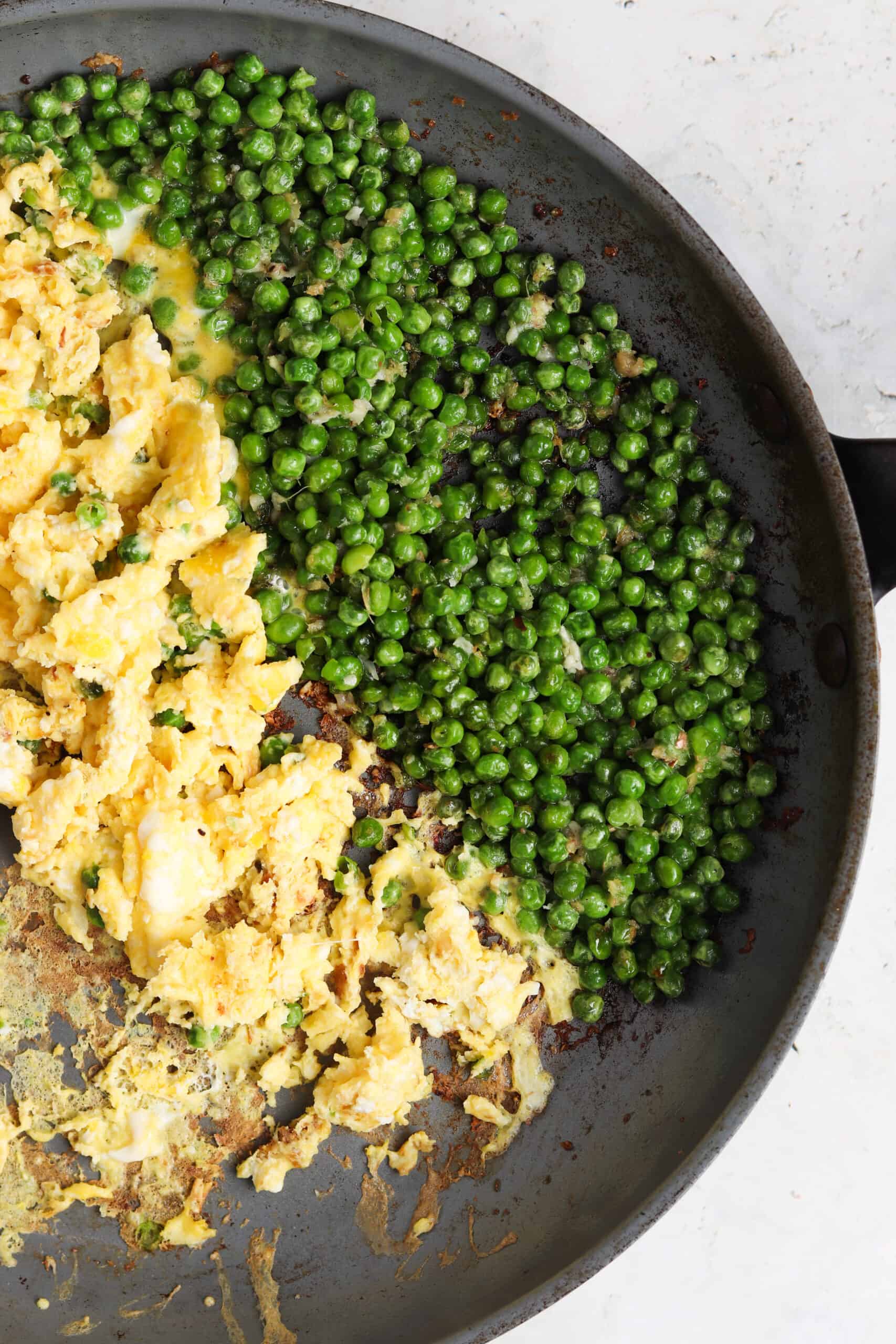 Peas and scrambled eggs for shrimp fried rice in a pan. 