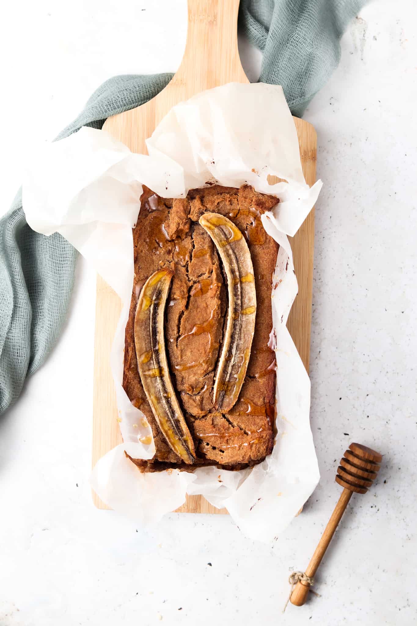 AIP Banana Bread on white wax paper on a wood cutting board with a green cloth.