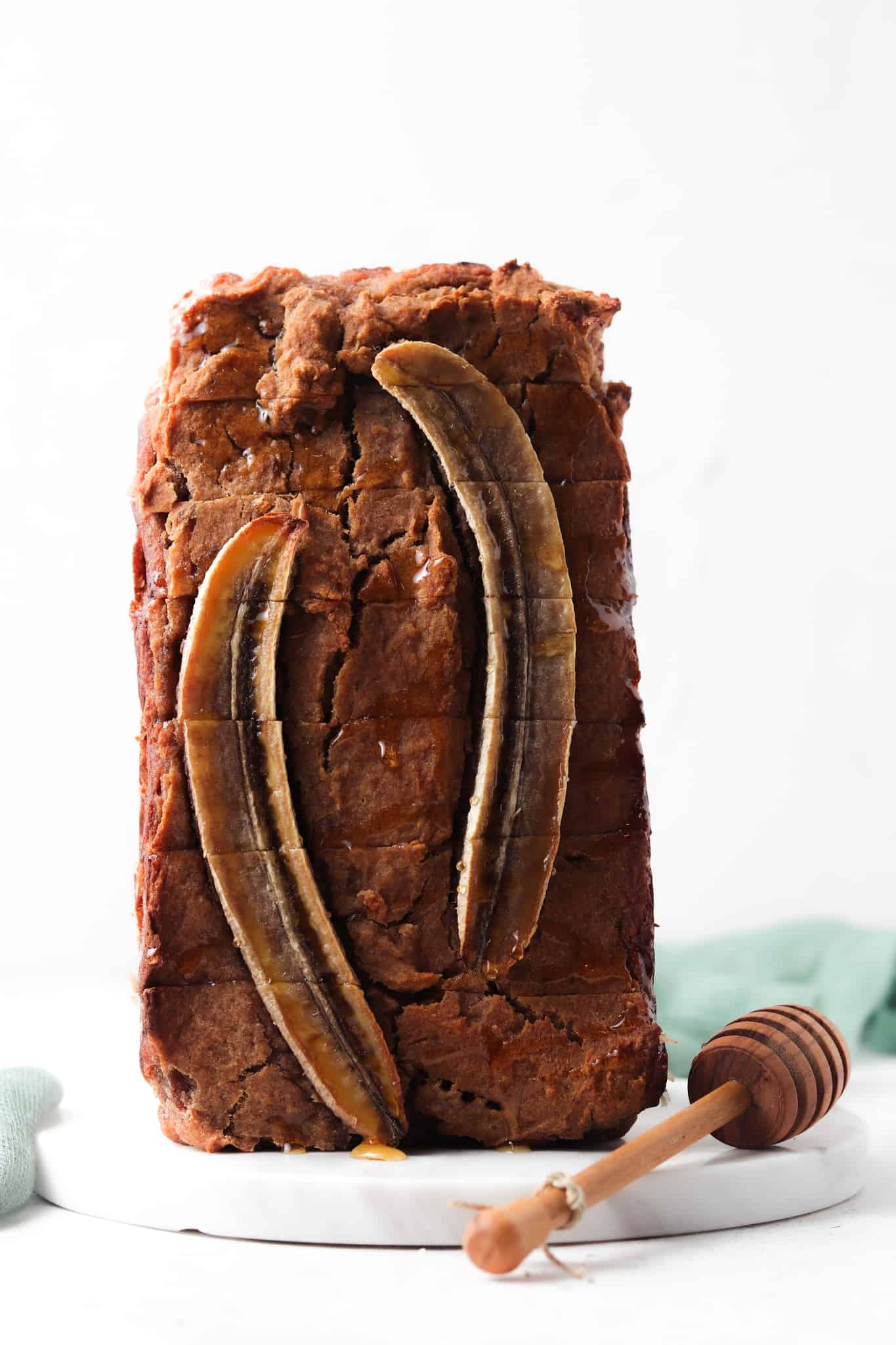 AIP Banana Bread cut and stacked on a white plate with a honey comb as garnish.