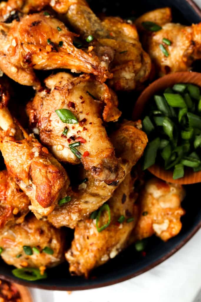 garlic butter wings on a blue plate with fresh chives