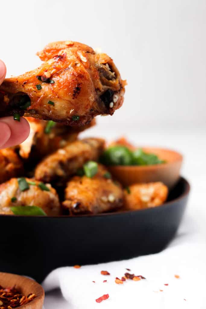 holding garlic butter wings over blue bowl