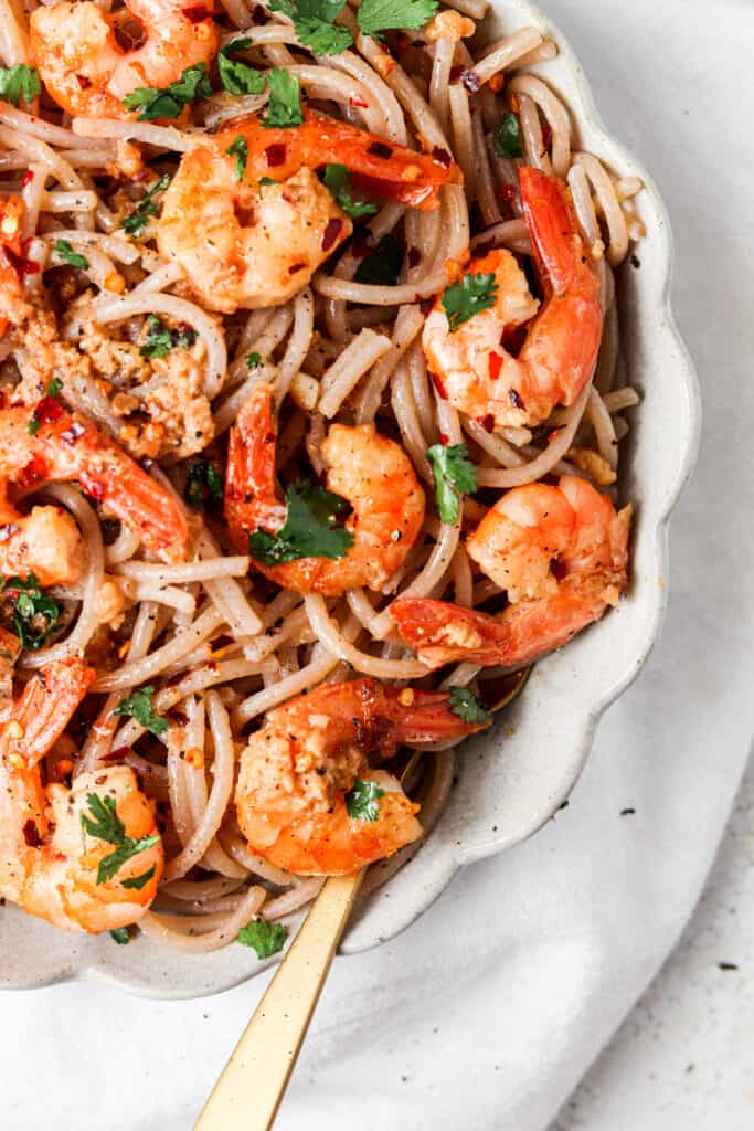 side shot of gluten free shrimp scampi in a bowl with a gold fork