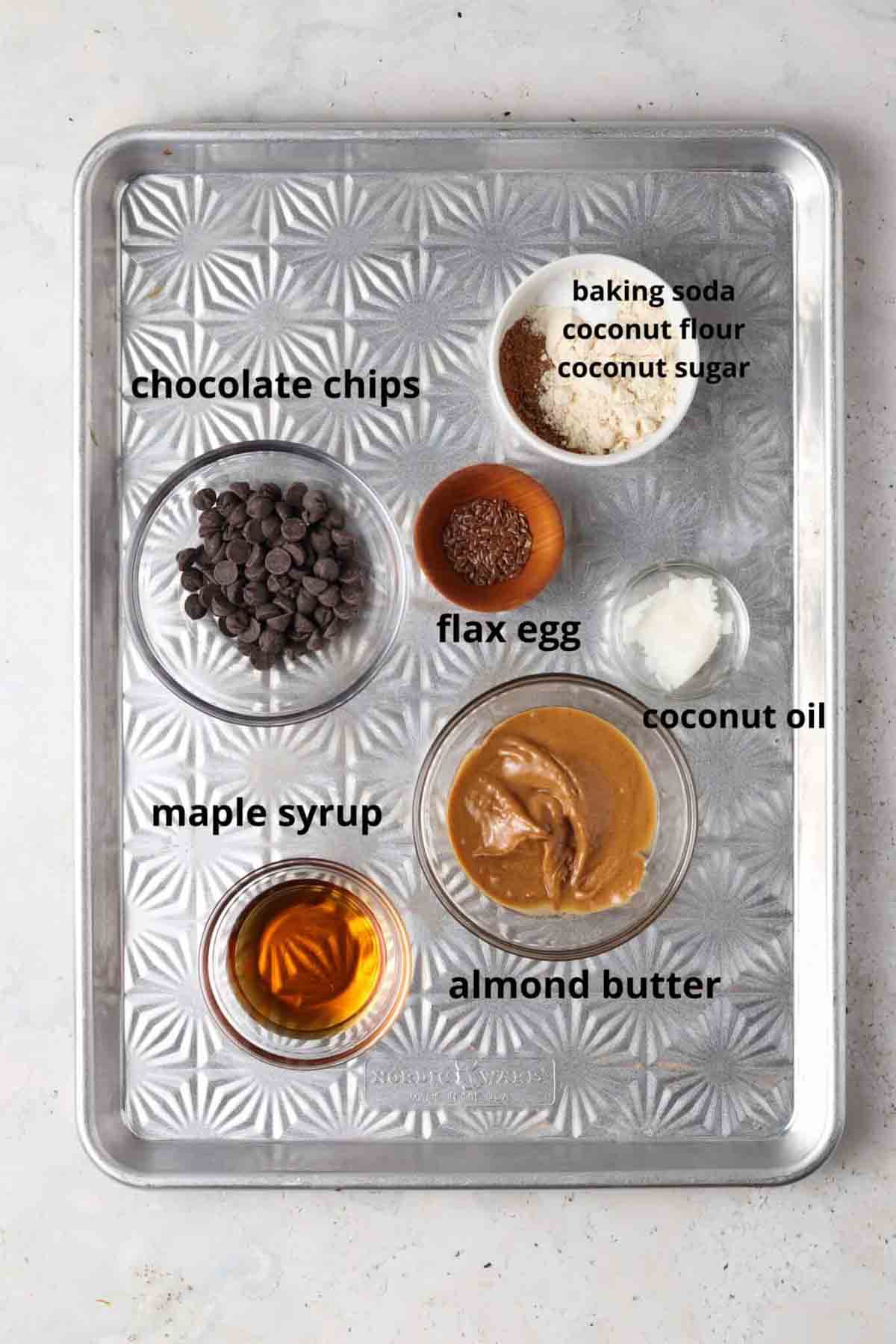 Recipe ingredients laid out on a baking sheet in glass clear bowls.
