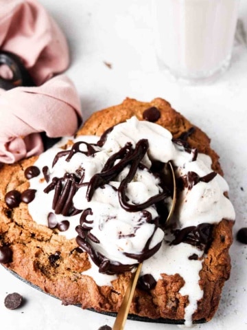 Chocolate chip cookie in a heart shape skillet with ice cream on top.