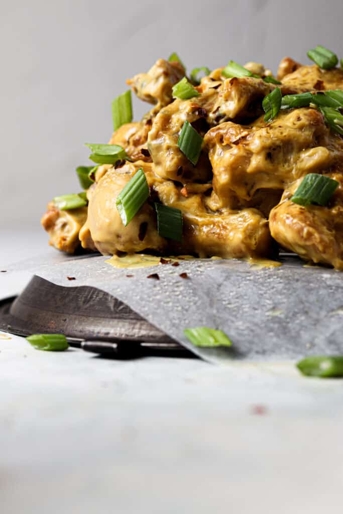 honey mustard chicken wings on a metal plate with green onions