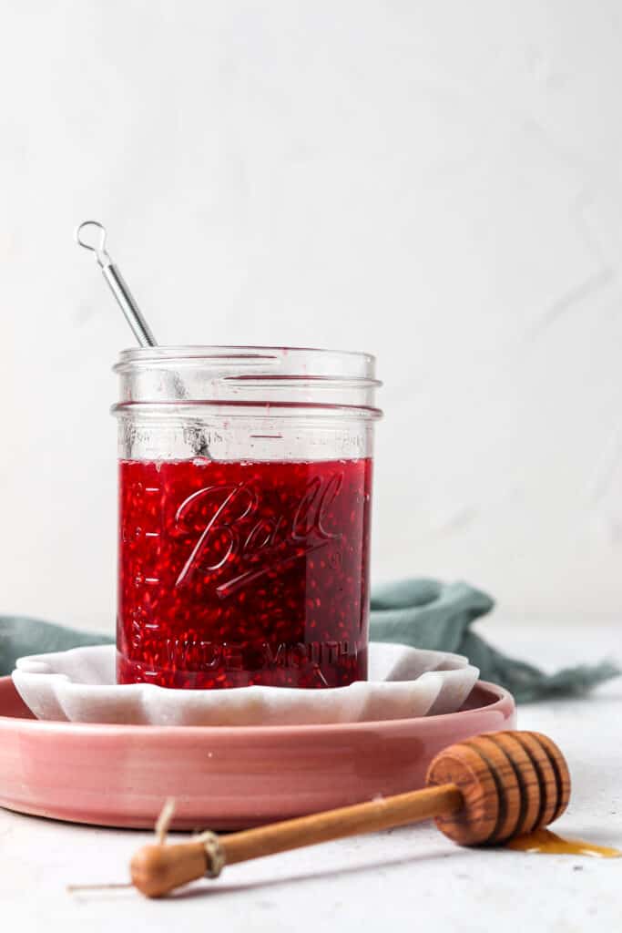 raspberry paleo jam in a mason jar with honey on the table