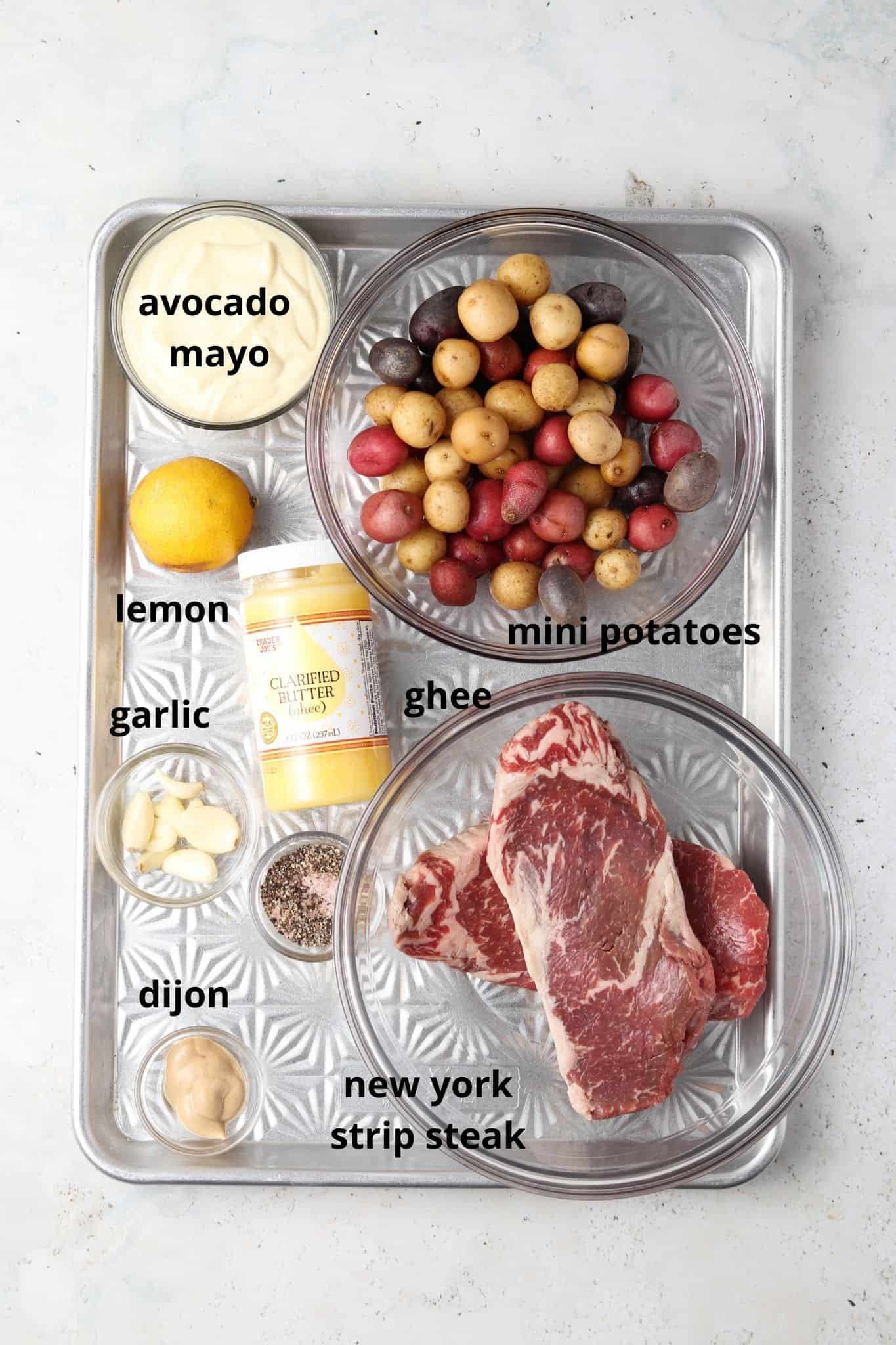 A steak date night ingredients in small glass bowls on a silver tray.