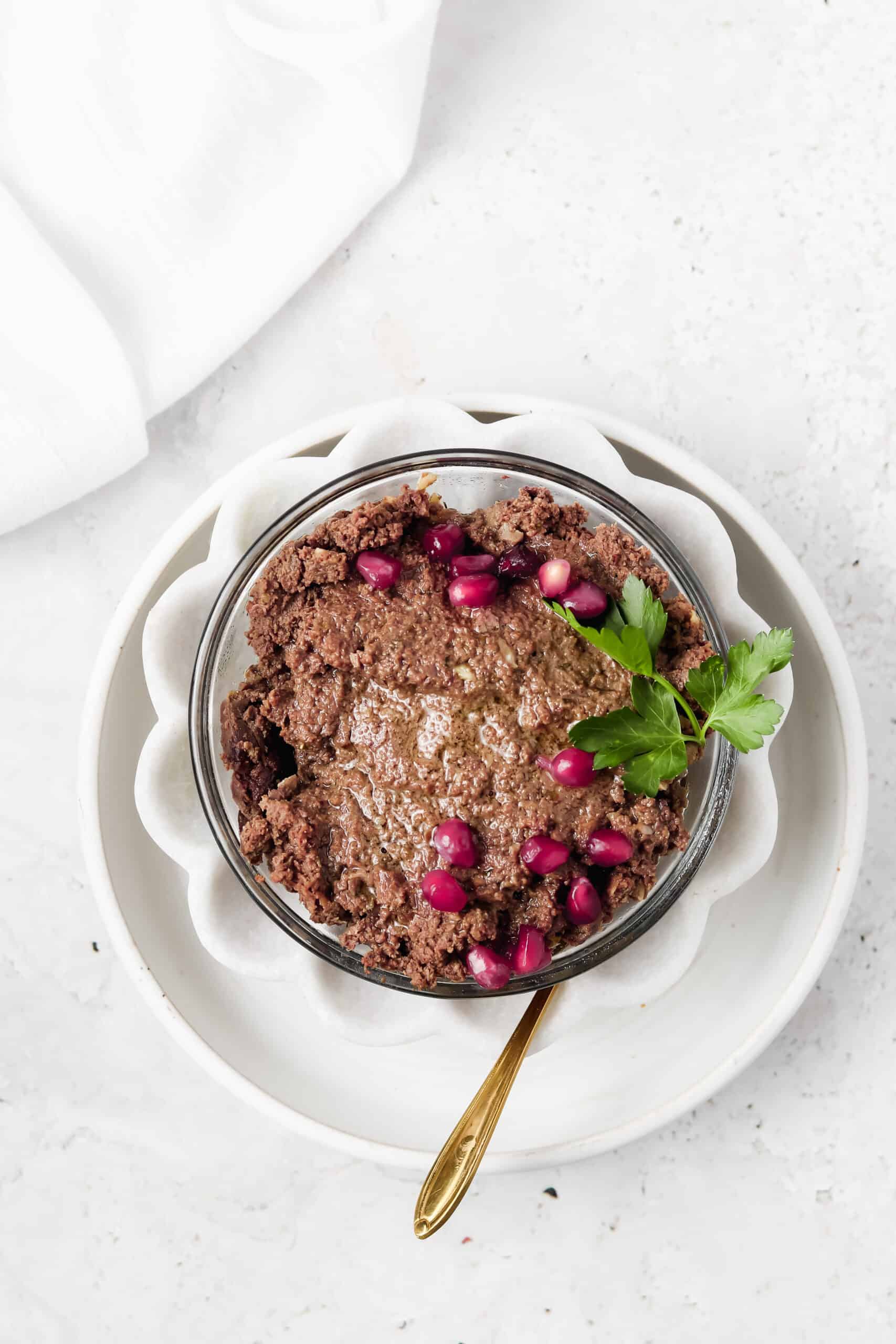 Beef liver pate in a flower white bowl with a gold spoon.