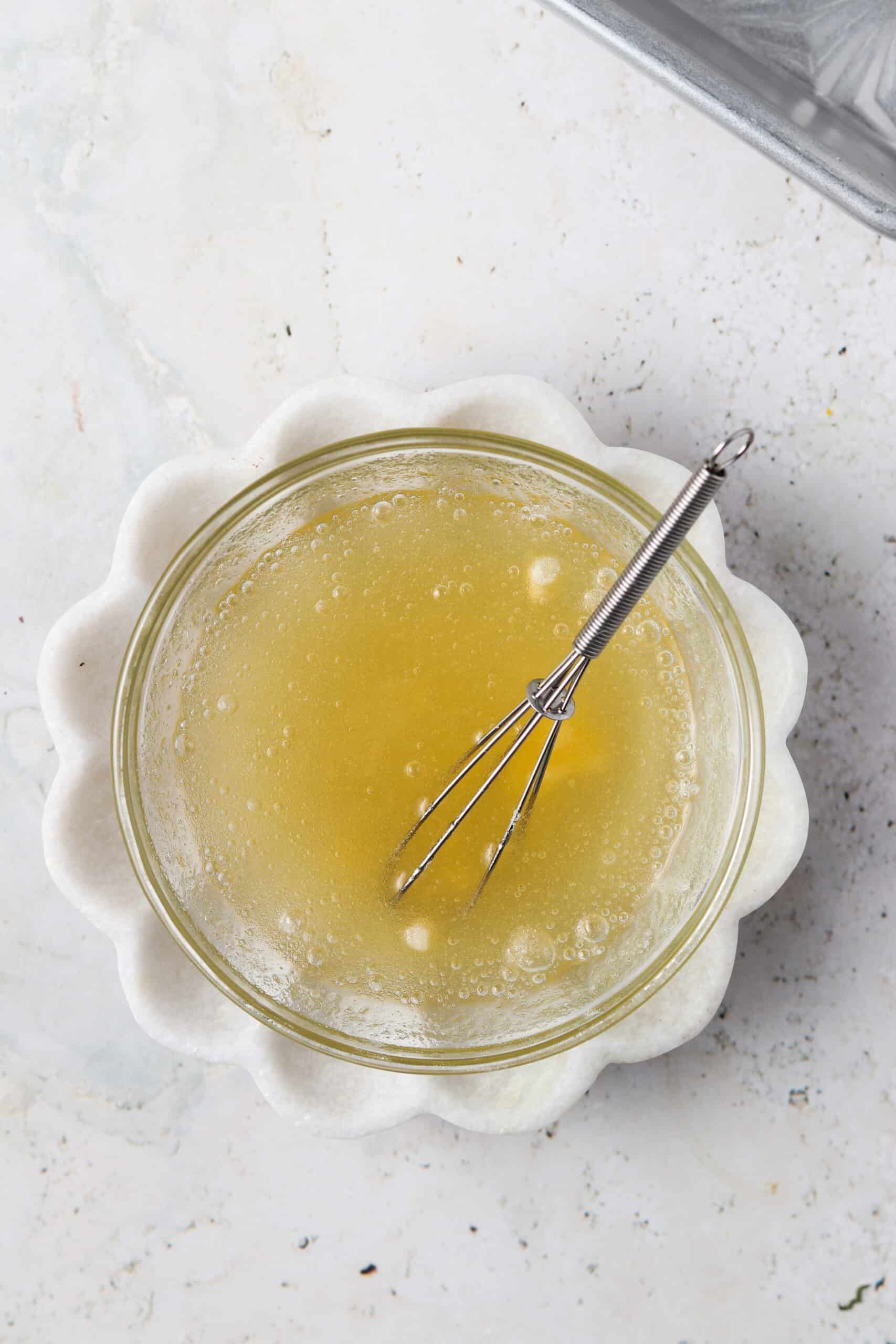 aip gelatin egg in a small glass bowl on a cream plate with a small whisk in the bowl