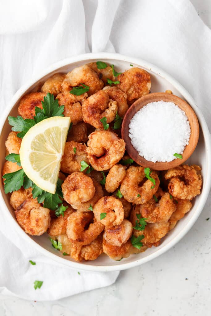 crispy shrimp on a white plate with a lemon and sea salt