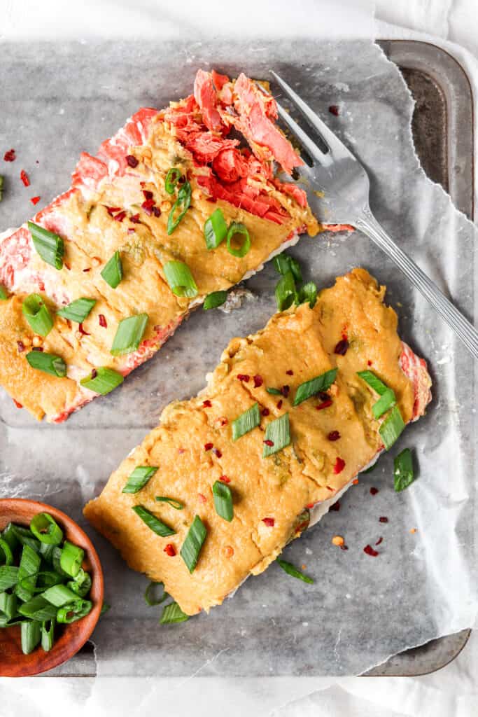 herb crusted salmon with a silver fork garnished with green onions