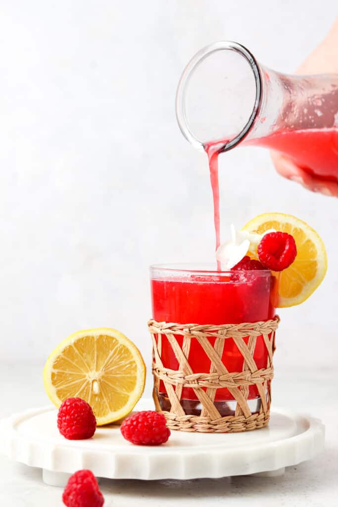 paleo raspberry lemonade with lemons on a tray in a clear glass