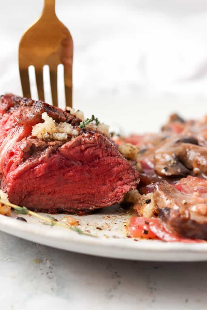 pan seared filet mignon with a fork in the middle of it