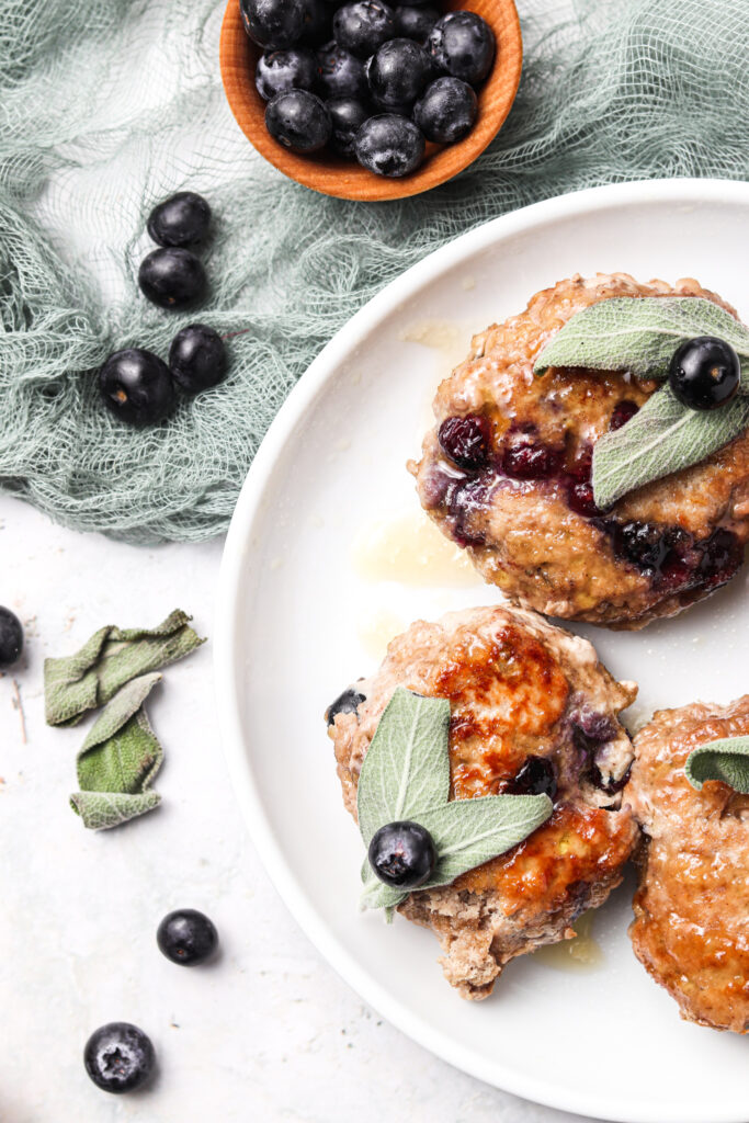 blueberry maple turkey breakfast sausage on a white plate with a pale green cloth next to it with garnishes