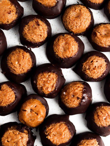 Peanut butter and almond butter buckeyes wrapped in chocolate on a plate.