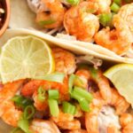 Buffalo shrimp tacos with green onions and lime on top.