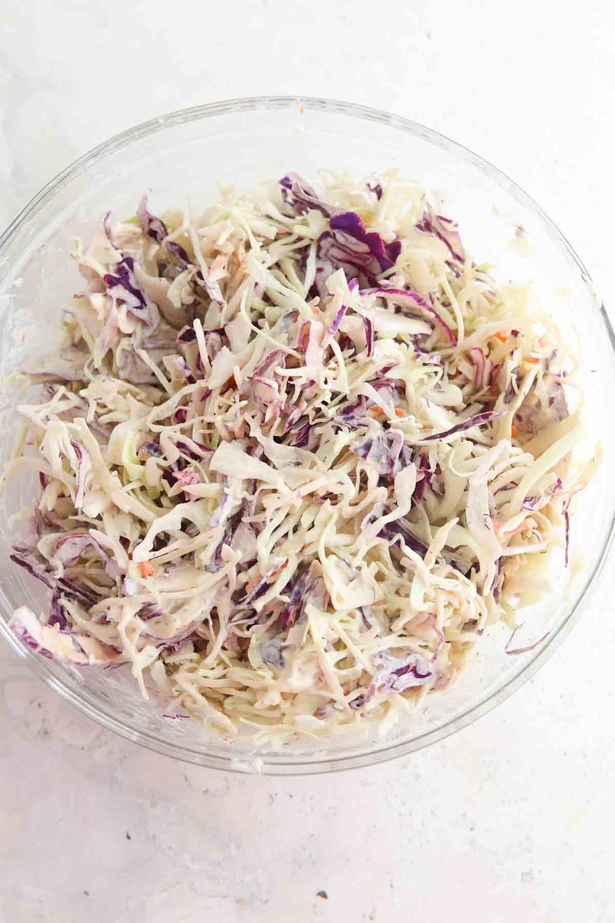 Coleslaw ingredients mixed in a large glass bowl.