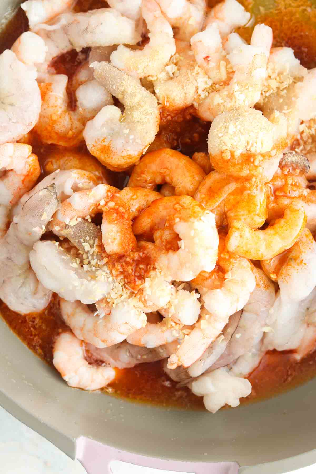 Shrimp, butter, buffalo sauce, and spices in a pan.