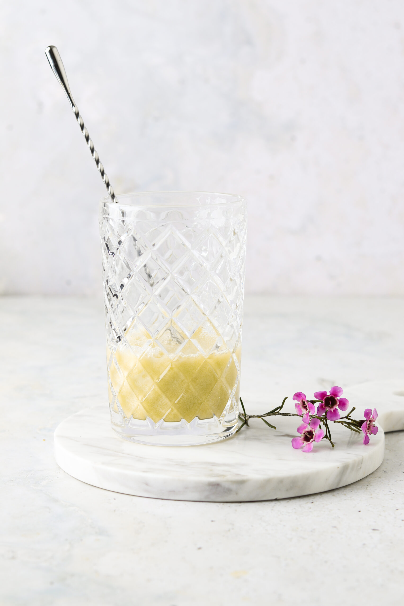 Coconut milk, pineapple juice and lime juice in a cocktail mixer with a large cocktail spoon.