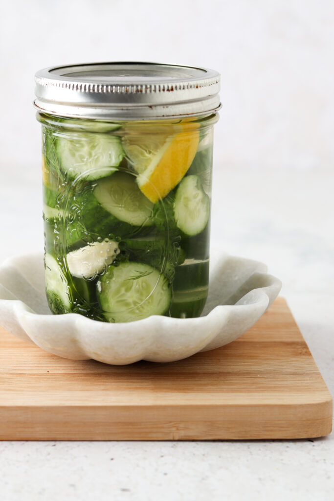 lemon cucumber pickles in a mason jar on a wooden plate