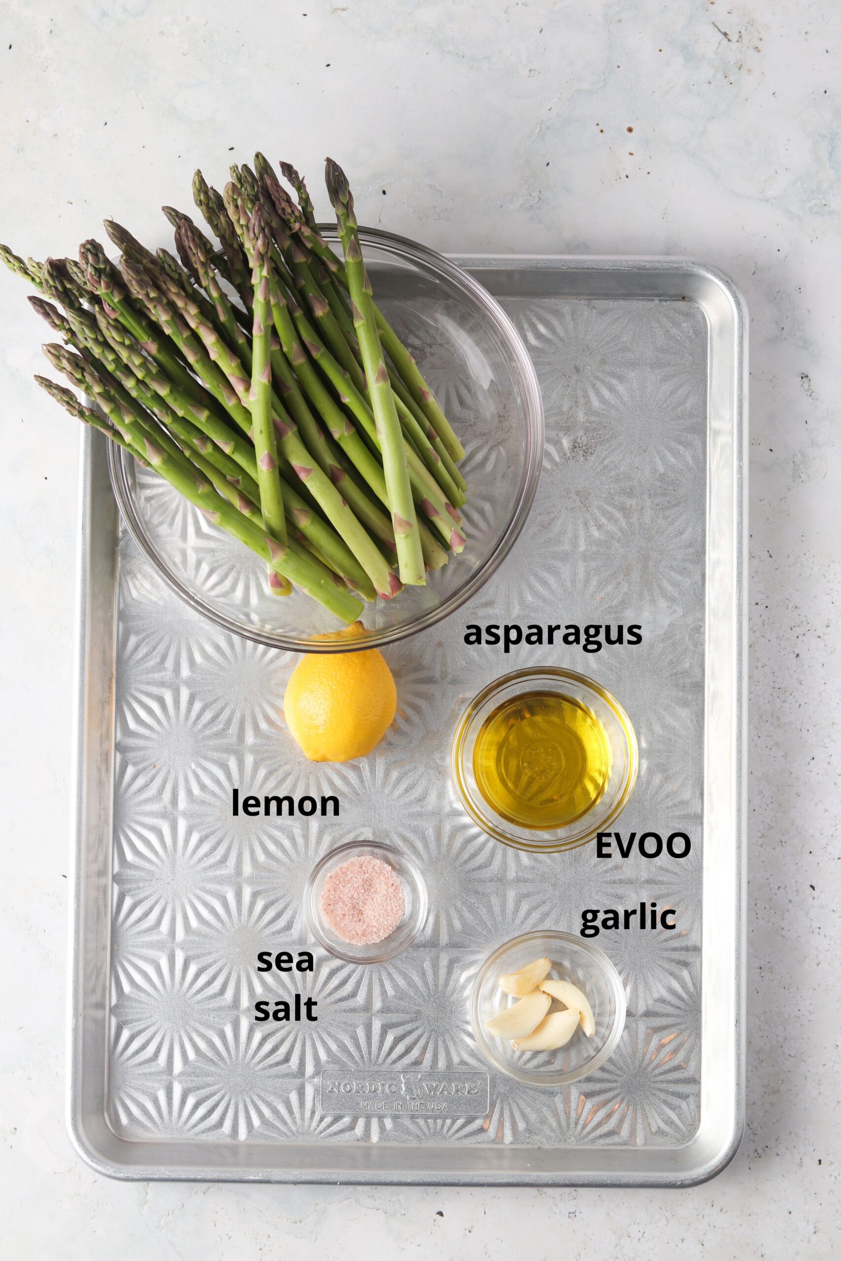 Asparagus ingredients in glass bowls on a metal tray.