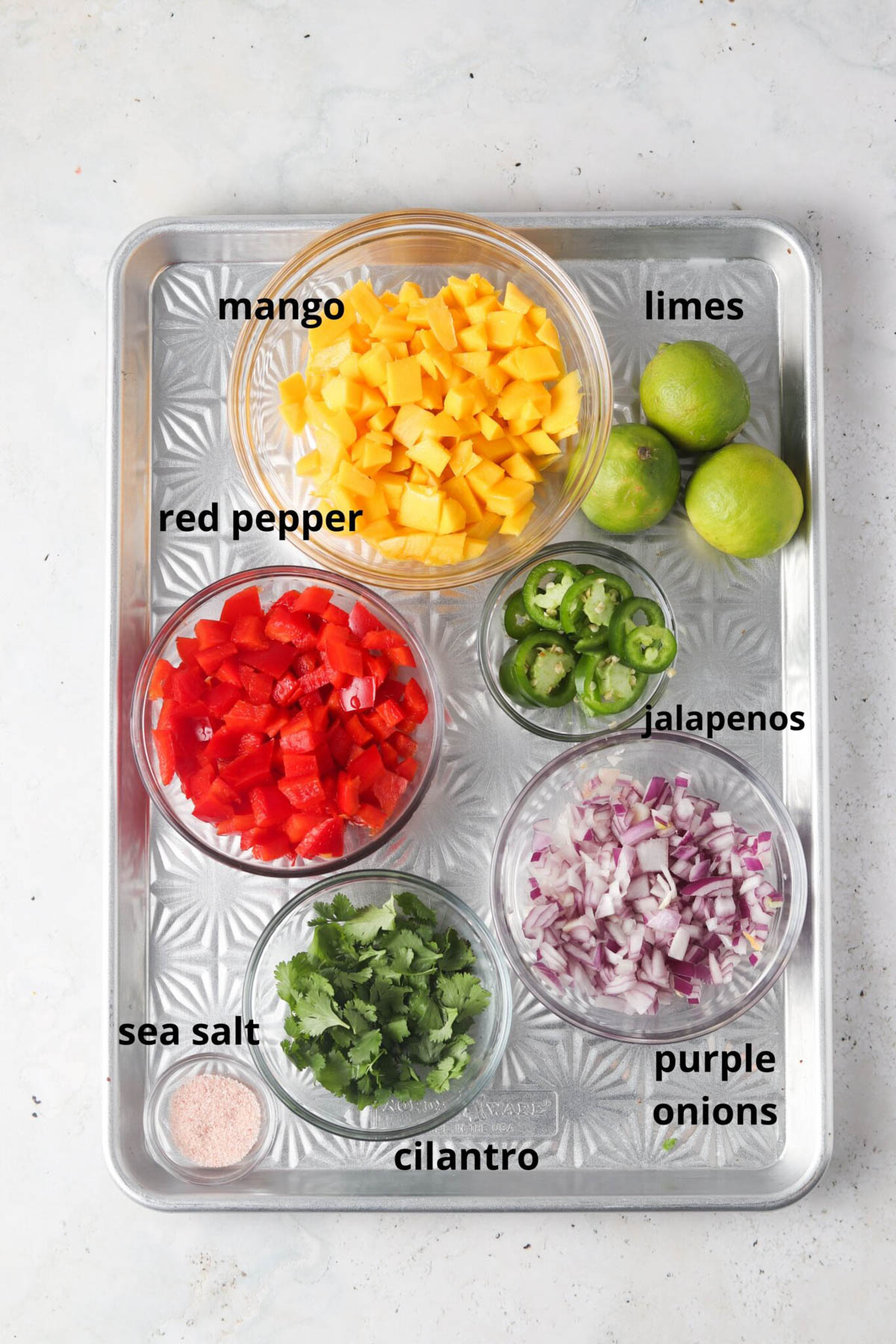 Mango pico de gallo ingredients in small glass bowls on a silver tray.