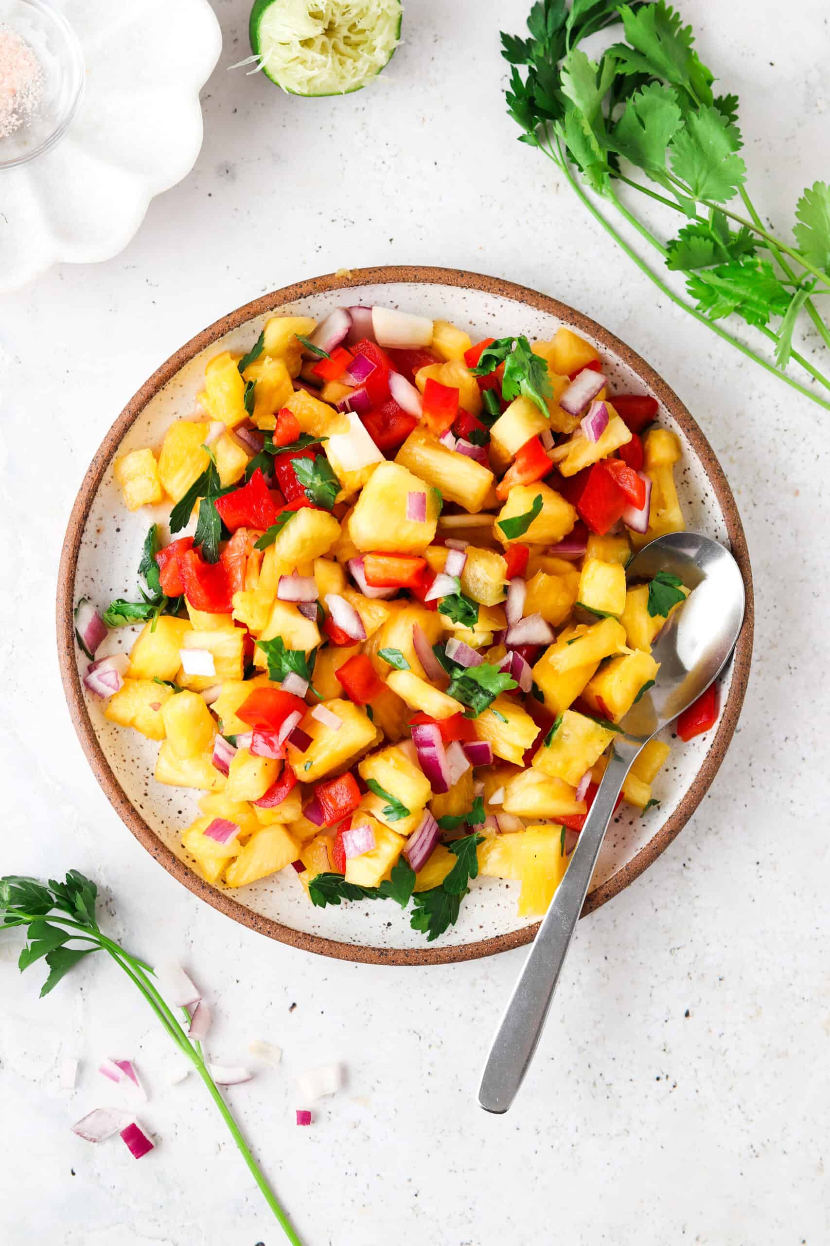 Pineapple pico de gallo on a plate with a silver spoon.