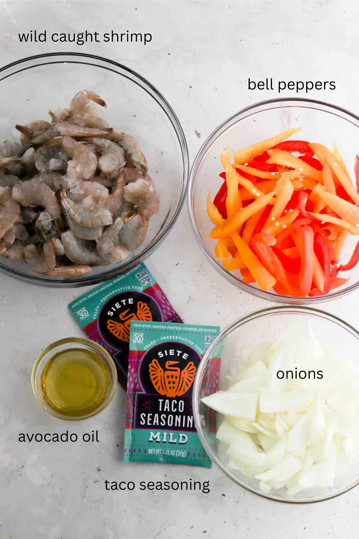 Shrimp taco ingredients laid out on the counter in glass bowls.