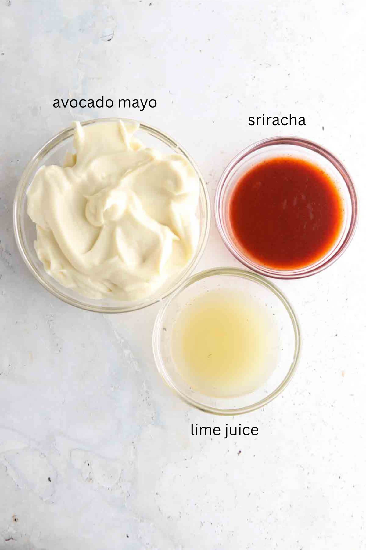 Spicy mayo sauce ingredients laid out in glass bowls. 