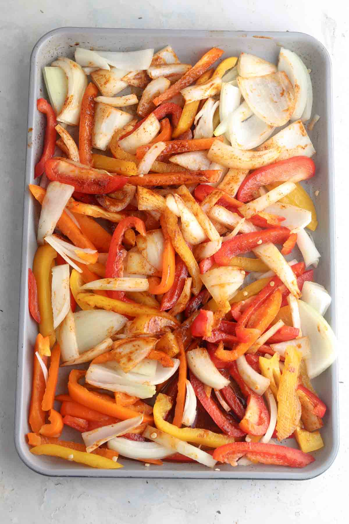 Marinated veggies laid out on a sheet pan.