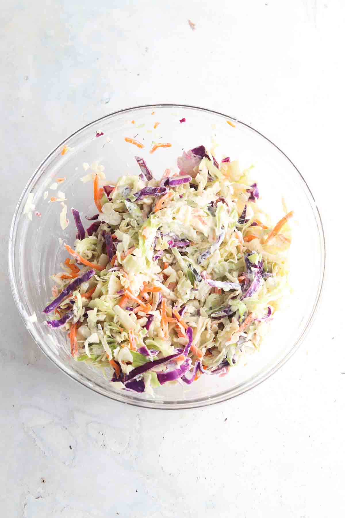 Slaw, avocado mayo and lime juice in a large glass bowl. 