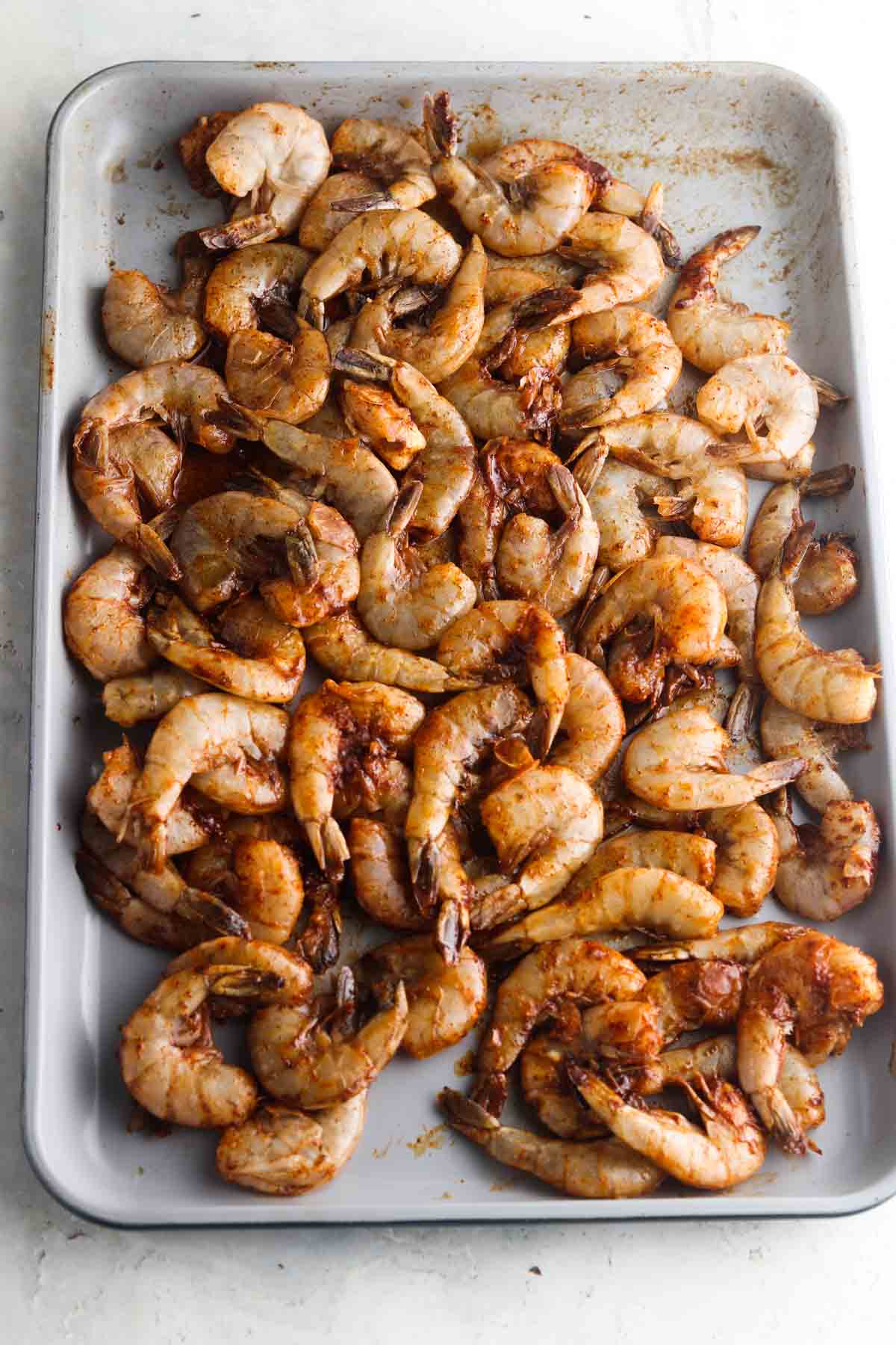 Marinated shrimp laid out on a sheet pan.