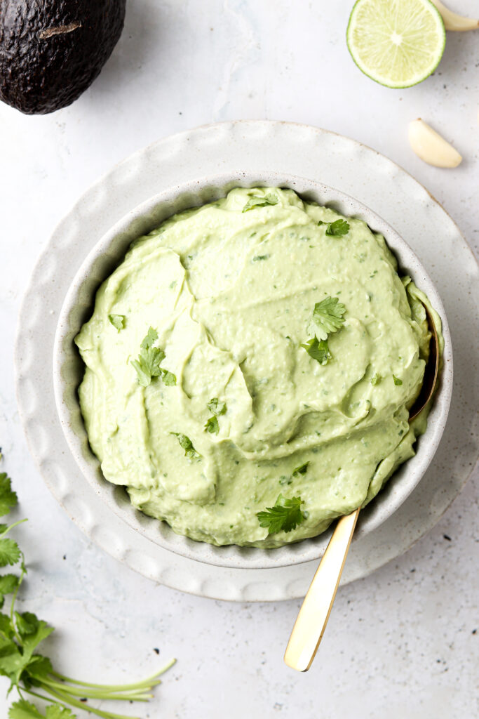 dairy free avocado crema in a bowl with limes