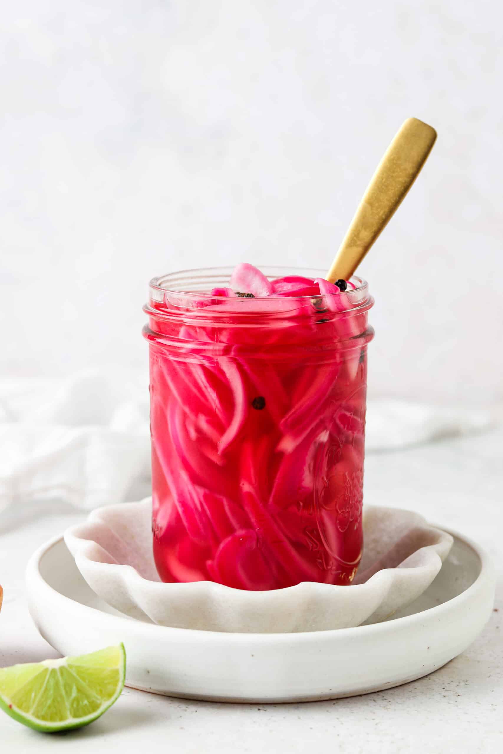 Sugar free mexican pickled onions in a mason jar with a gold spoon on a platter.