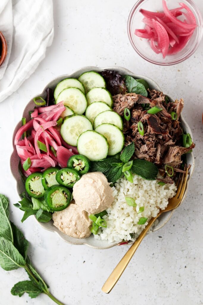 far away picture of shredded lamb power bowls with a ton of vegetables in a bowl