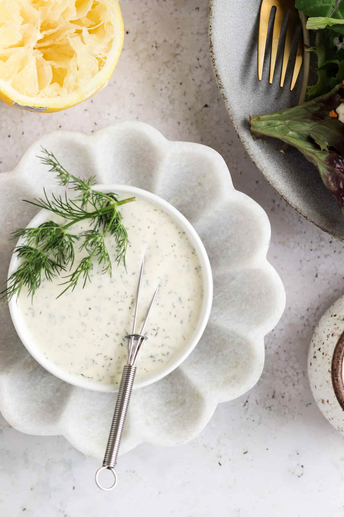 Dairy free dill aioli in a small white bowl with a small metal whisk in it. 