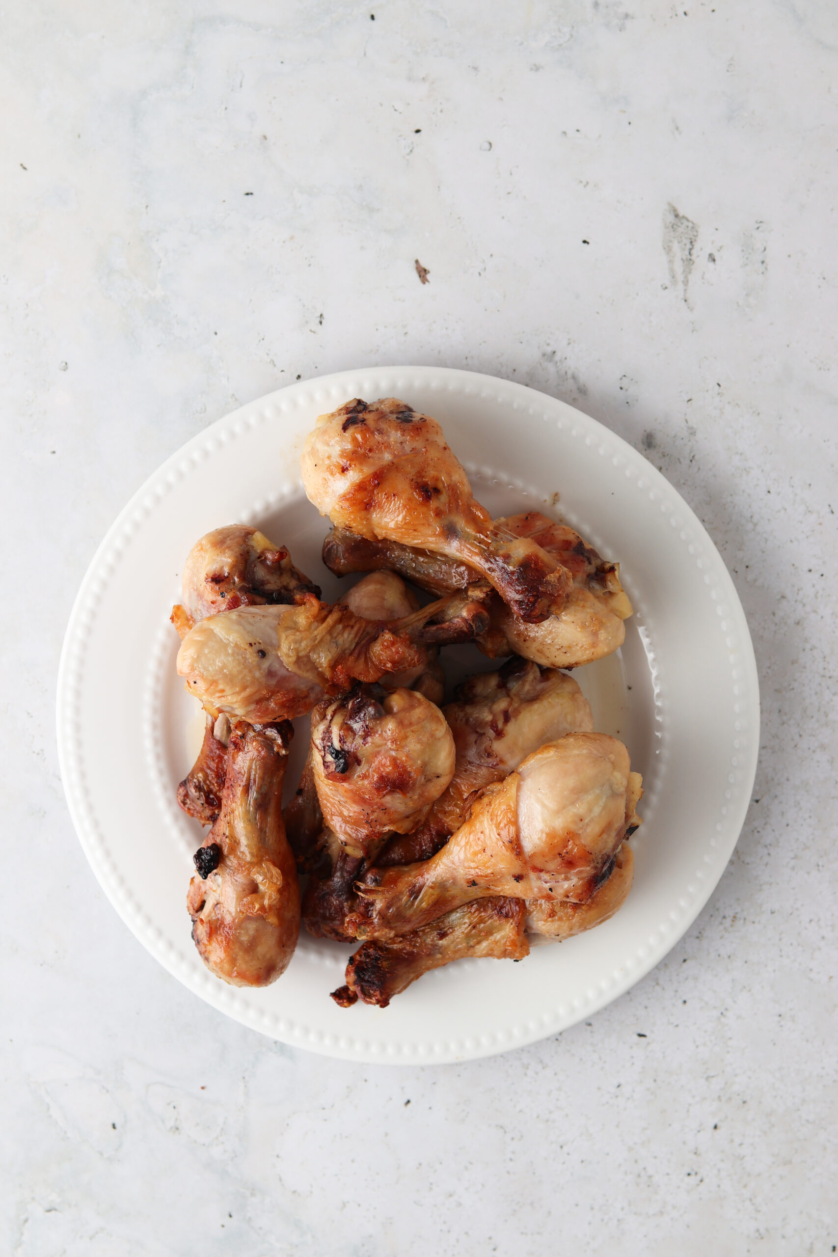 Grilled chicken drumsticks on a white plate. 