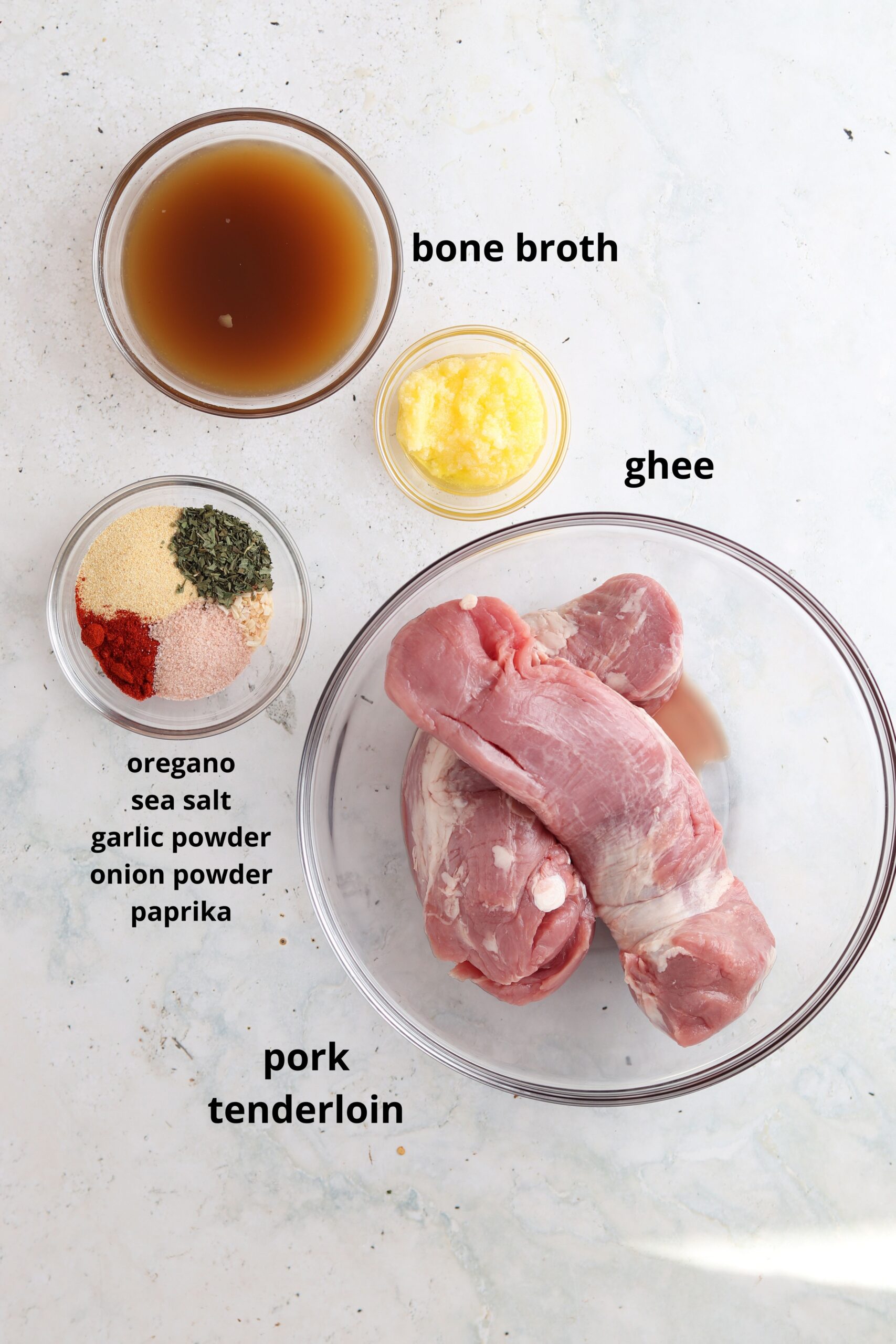 Whole30 pork tenderloin with herb crust ingredients in small glass bowls on white surface.