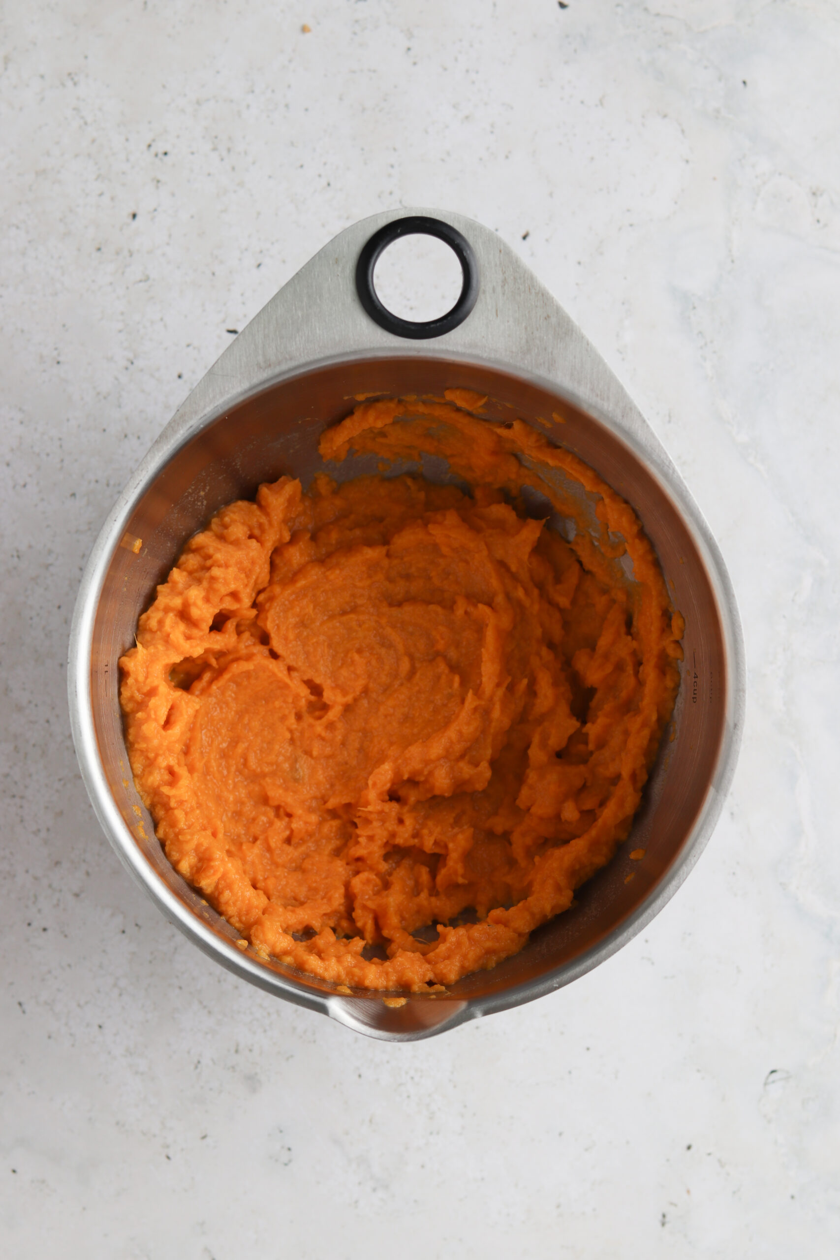 Sweet potato mash with olive oil, sea salt and pepper in a stainless steel bowl.