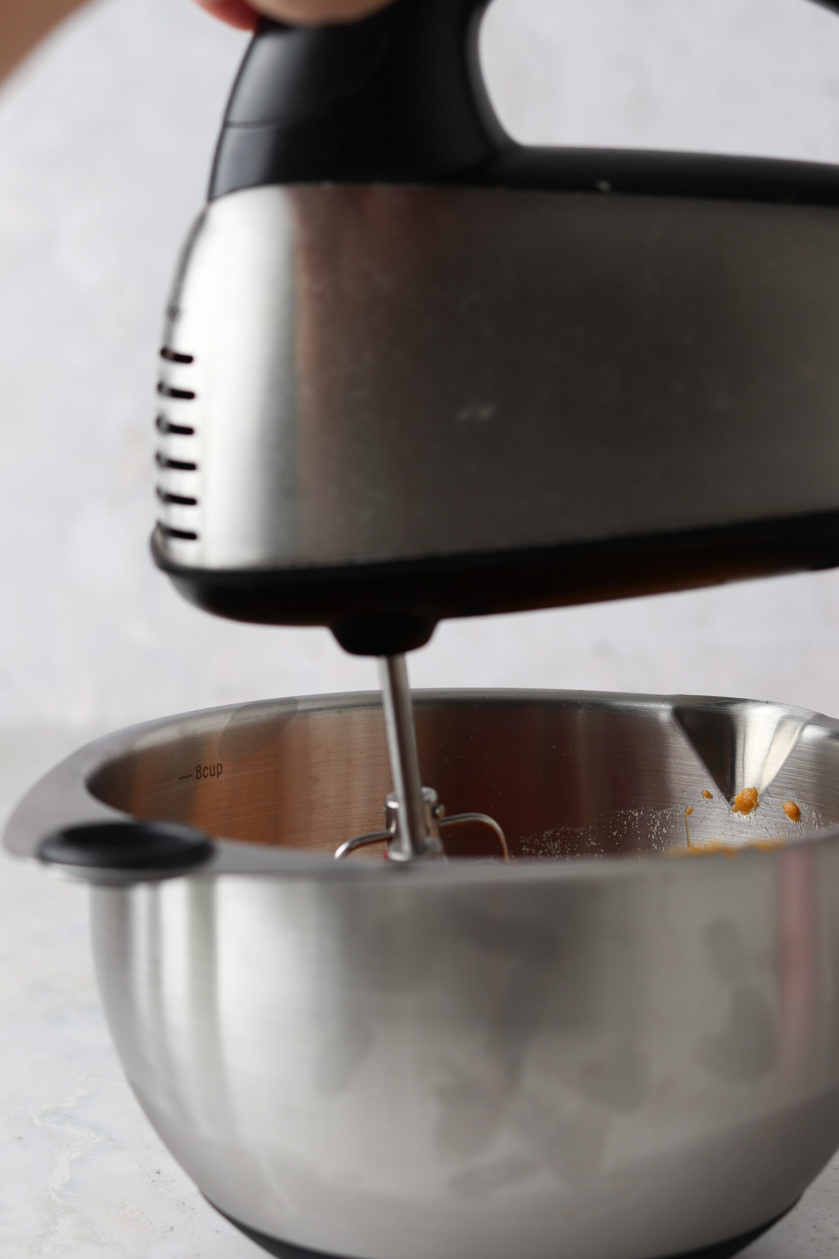 Handheld food processor whipping up sweet potatoes in a metal bowl.