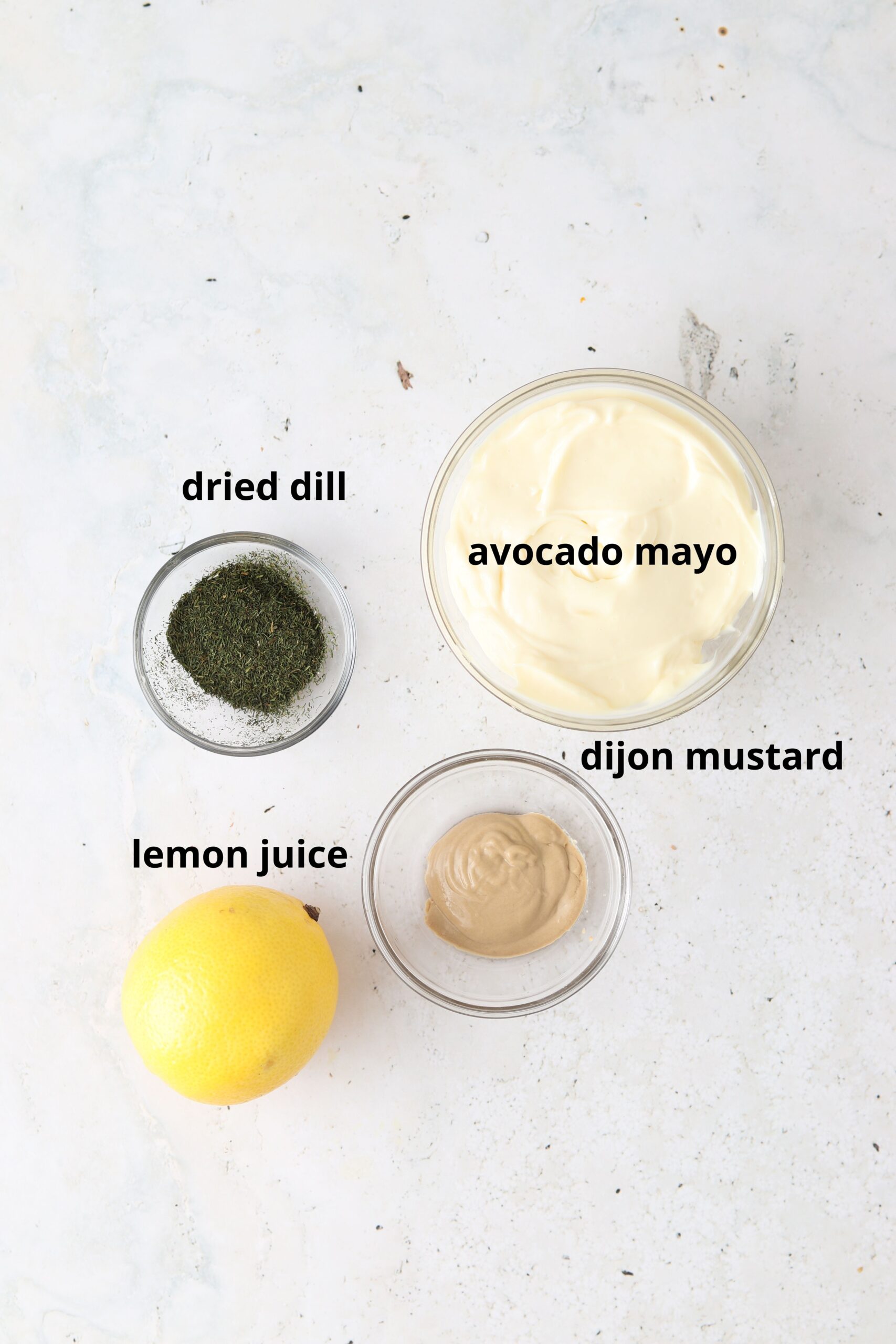 Dill aioli ingredients in small glass bowls laid out. 