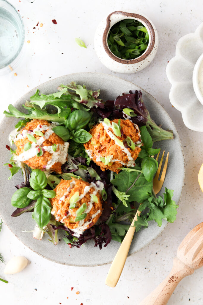 salmon cakes on a bed of greens with aioli sauce on top