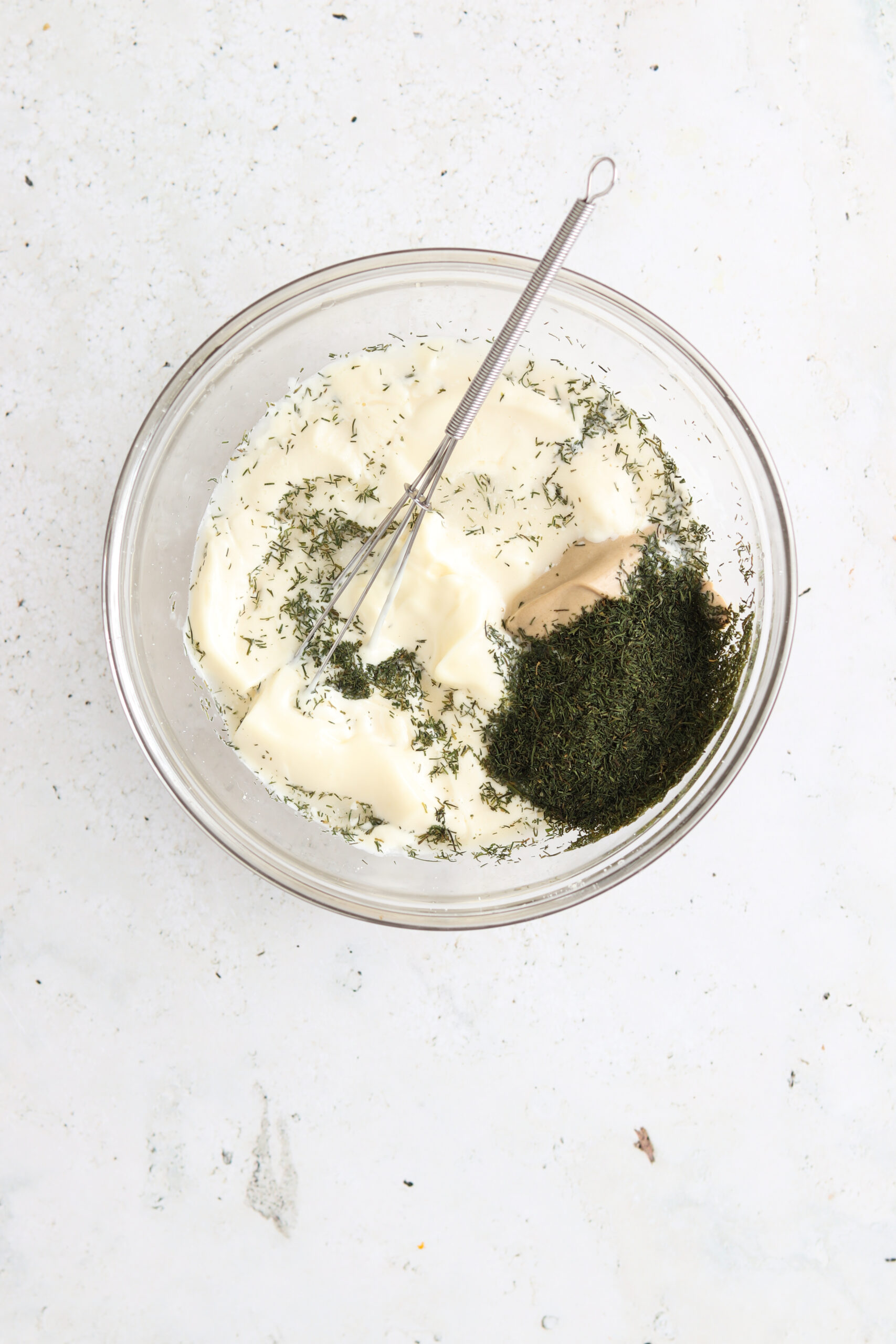 Dill aioli ingredients in a glass mixing bowl. 