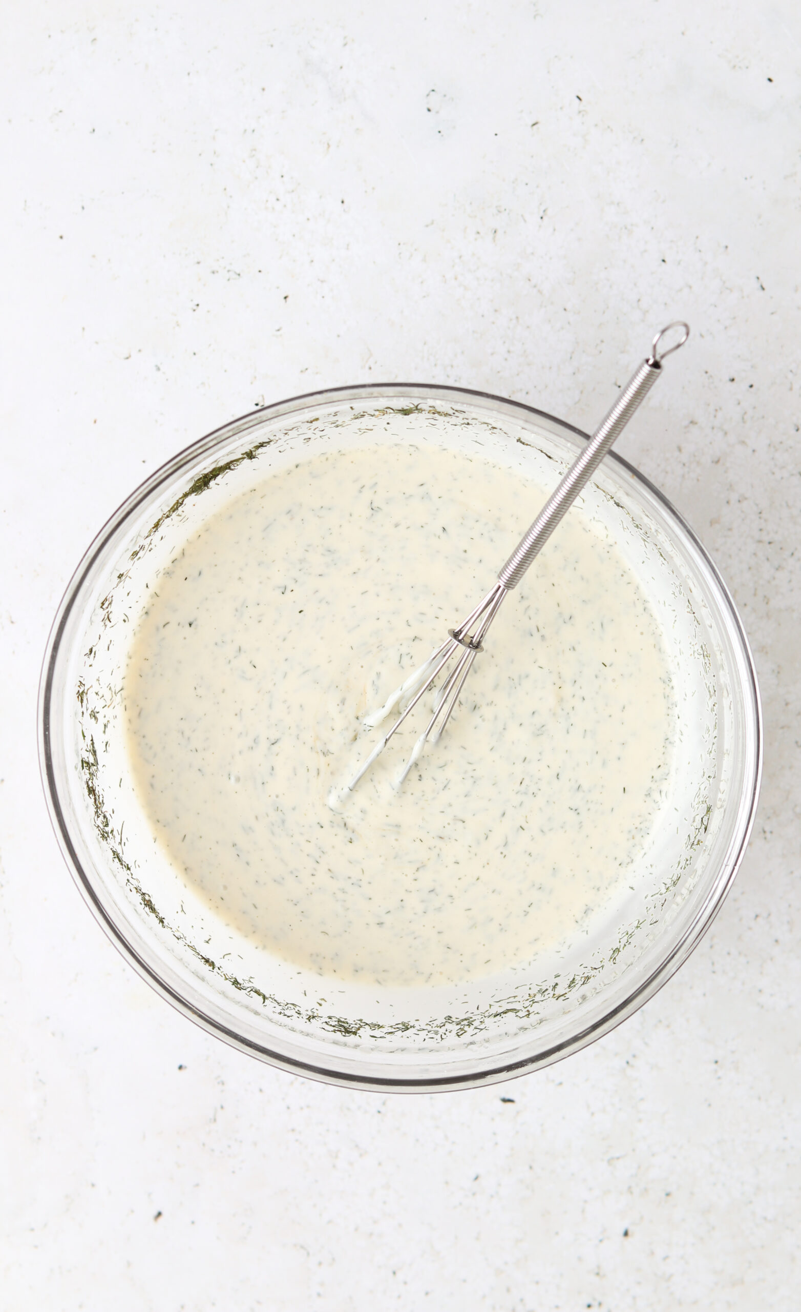 Dill aioli mixed together in a glass mixing bowl.